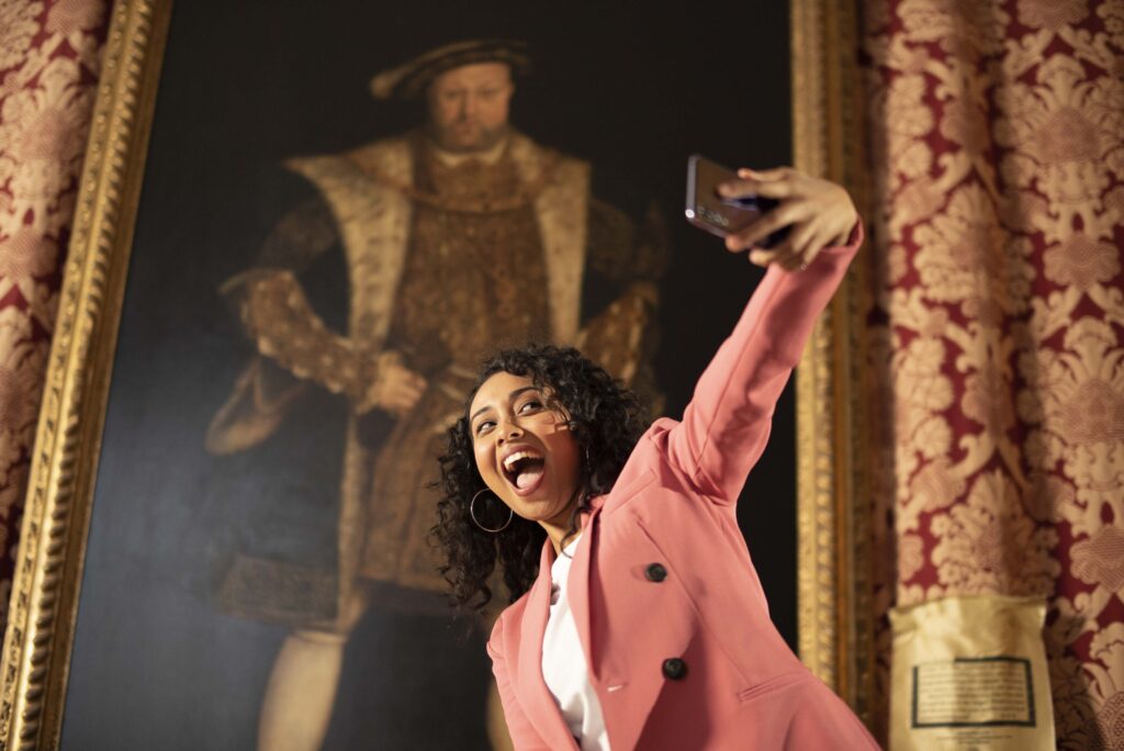 Tracey Tooley taking a selfie in front of Henry VIII wall portrait
